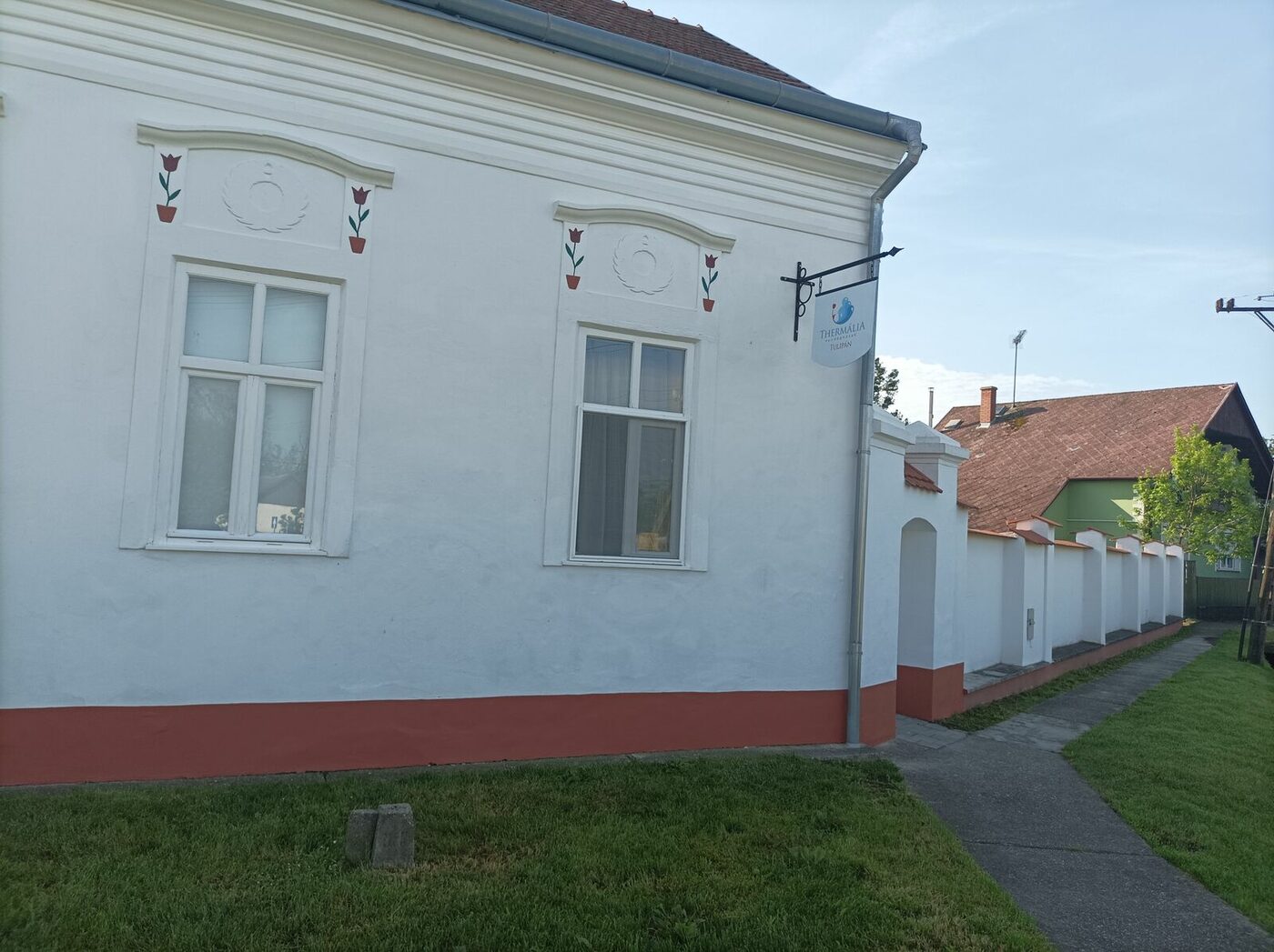 A Tulipán Vendégház fehér, piros lábazatú utcafronti homlokzata Kabán